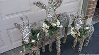 Front view of three twine-wrapped wire reindeer with greenery collars
