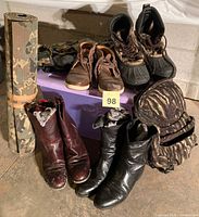 Group shot showing all items: rolled camo pad, three boot pairs, casual shoes, camo hat, pouch, small backpack