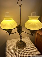 Full view of lit brass double student lamp with yellow ribbed shades and chimneys