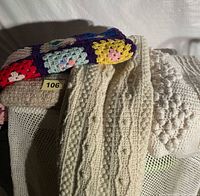 Group of blankets showing colourful granny square afghan and two cream throws with cable and popcorn textures