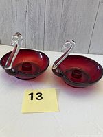 Front view of both ruby red swan candle holders showing clear necks and candle cups