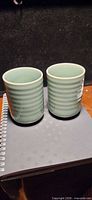 Front view of both green ribbed tea cups