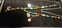 Full view of necklace showing bead colours, coin dangles and chain clasp