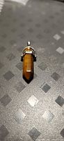 Front view of tiger eye pendant showing hexagonal prism and pointed end