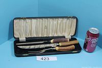 Open case showing knife and fork with antler-style handles inside satin-lined interior