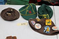 Four hats laid out: brown beret, two green caps, brown bucket hat