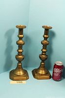Pair of brass candlesticks next to soda can for scale