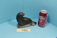 Front view of stone seal figurine beside soda can for scale