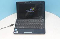 Front view of Asus Eee PC laptop open and powered on to Windows XP screen, power cable attached