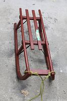 Top view of red wooden sleigh showing four seat slats and pull rope