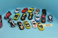 Frontal view showing all 13 complete slot cars and 3 spare bodies with a can for scale