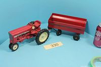 Side view of red International Harvester toy tractor and red metal trailer together
