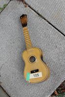 Front view of Lark soprano ukulele on carpet showing body, neck, strings and finish damage