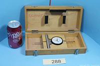 Gage in open wooden case beside soda can for scale