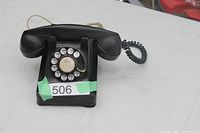 front view of black rotary dial phone showing dial and base