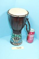 Full view of djembe next to soda can for scale