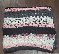 Folded multicolour crochet blanket showing stitch detail and colour palette