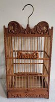 Front view of carved wood bird cage with hook