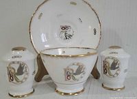 Front view of sugar bowl, saucer and shakers showing pattern and gold trim