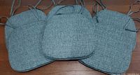 Three of the blue-grey chair pads showing fabric texture and ties