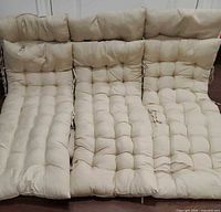 Six beige tufted chair cushions laid out side by side