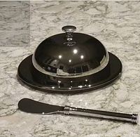 Stainless steel domed butter dish with spreader on countertop