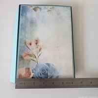 Front cover with floral design alongside ruler showing width ~5.25 inches