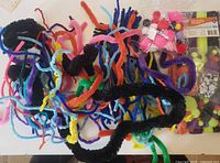 Pile of multicolor pipe cleaners with bagged pom poms and googly eyes