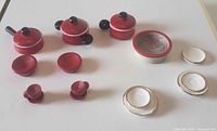 all red pots, bowls, cups and white plates displayed