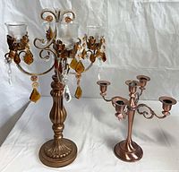 Two metal candelabras side by side showing relative size and color
