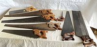 Seven hand saws laid out on table showing overall lot
