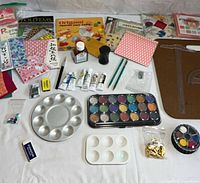 All items laid out showing origami paper packs, paint palettes, tubes, board and accessories