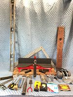 Overview of lot with miter box, levels, square, tools, safety gear