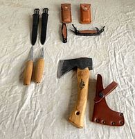 Group shot of hatchet, carving knives, multi-tool, sheaths