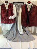 Group shot of two vests, two shirts and striped skirt displayed on hangers
