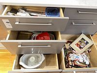 Open drawers showing Crock-Pot insert, plastic containers, assorted utensils and placemats