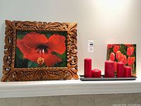 Overall view of framed hibiscus print, tulip canvas, four red candles on black tray