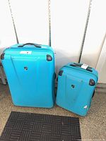 Front view of both teal Heys hard shell suitcases showing size difference and exterior condition