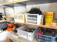 Shelf with multiple baskets containing clamps, goggles, rope and accessories