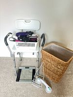 Overall lot showing shower chair, hamper, scale, wire holder, basket with hair tools