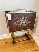 Trays stacked on wheeled stand showing front decorative motif