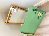 Wooden adjustable tray leaning against wall beside green painted tray
