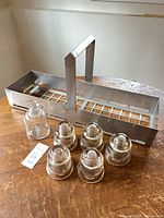 Full lot showing five glass insulators, small glass vase, metal carrier