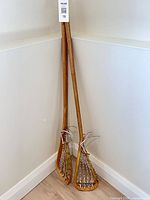 Two wooden lacrosse sticks standing in corner