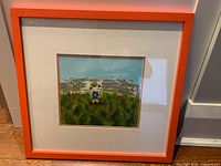 Front view of framed painting showing artwork, mat and orange frame