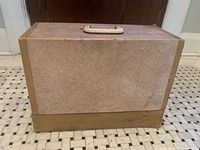 Closed tan hard carrying case standing upright