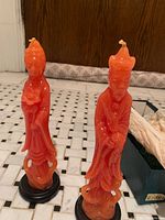 Pair of orange wax ceremonial candles on black bases standing upright