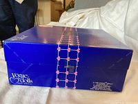 Closed blue Vogue Dolls box with pink heart border, side view