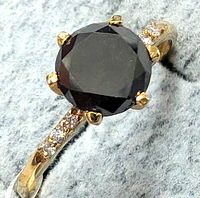 Top view showing round black diamond in six-prong yellow-gold setting