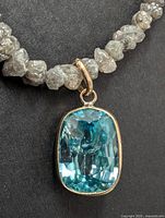 Close-up of blue zircon pendant and adjacent rough diamond beads